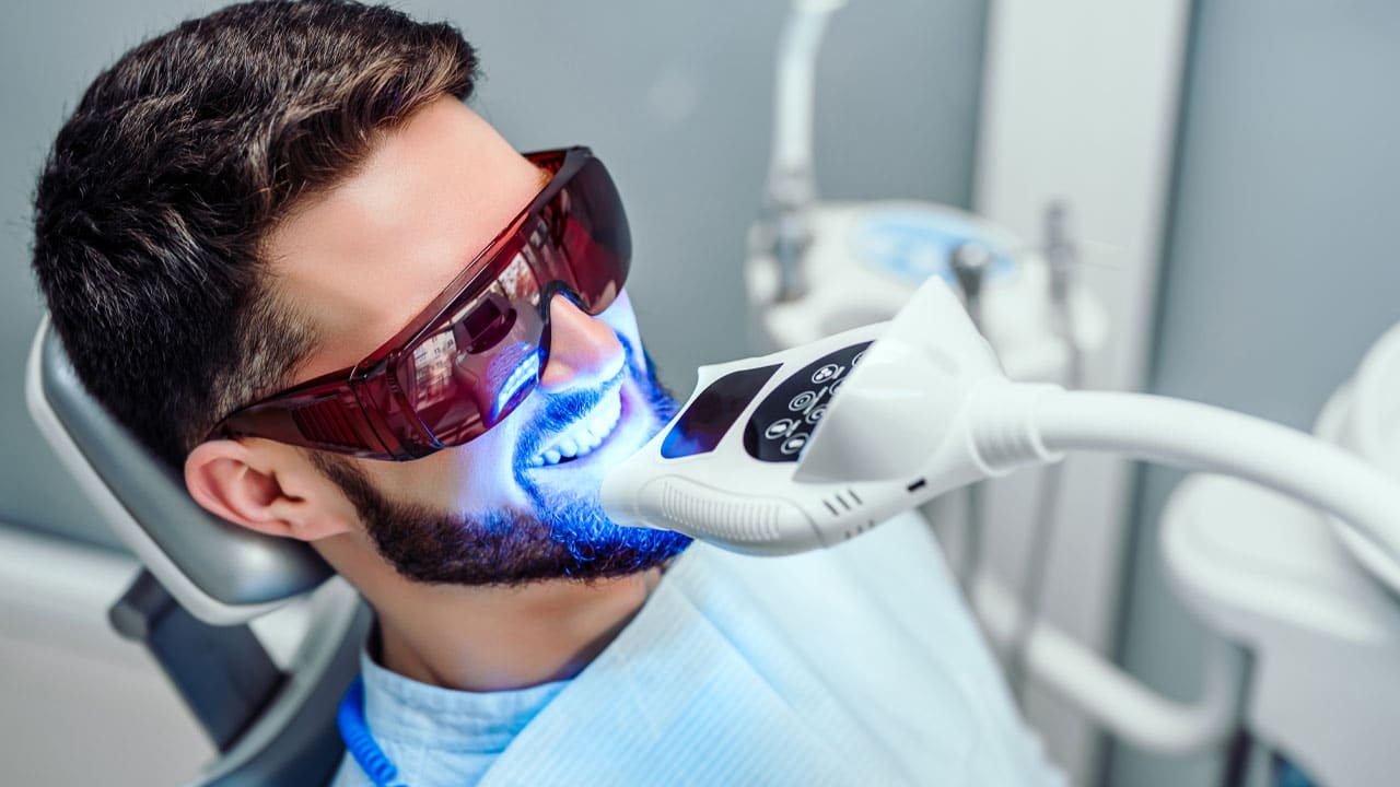 Man sitting in a dental chair getting his teeth whitened