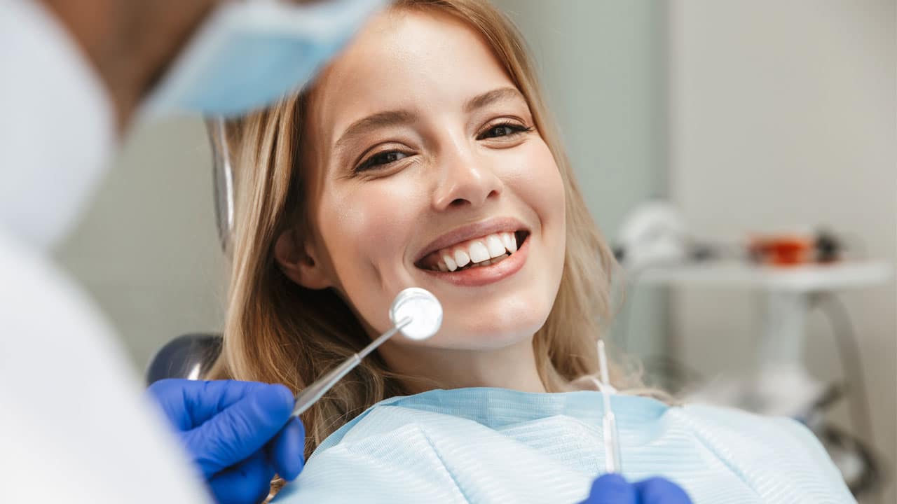 Young woman sitting in a dental chair and smiling at the camera
