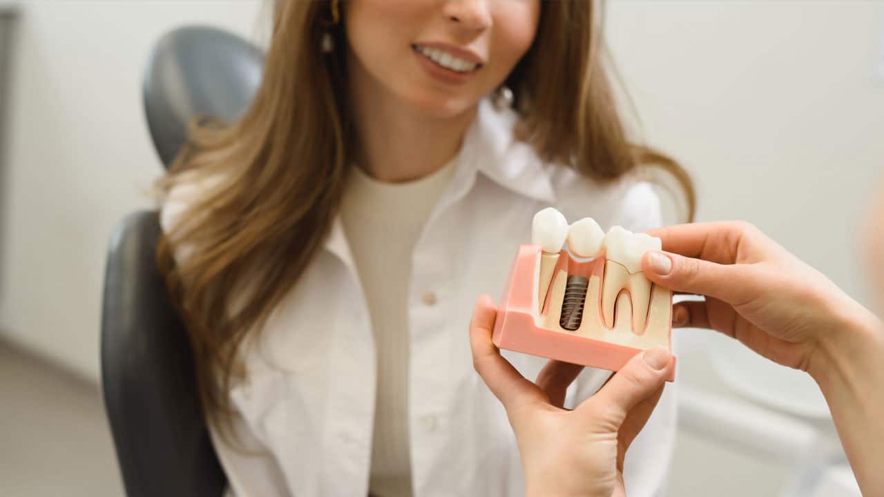 Woman at the dentist looking at a tooth model with her dentist