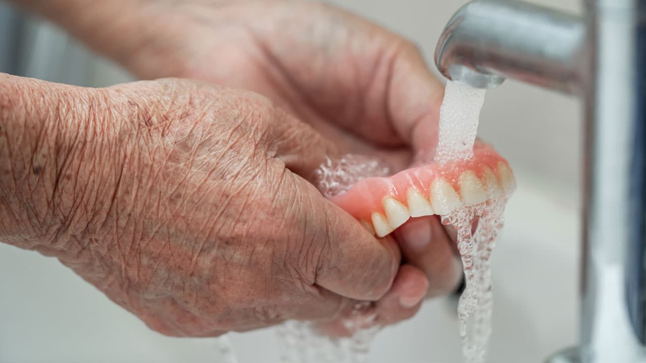 Elderly patient holding and washing denture