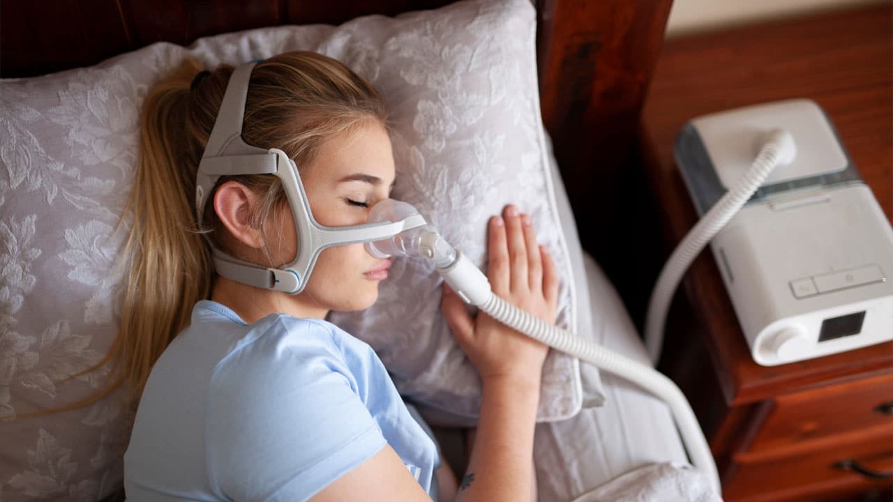 Young woman sleeping in bed a with sleep apnea machine