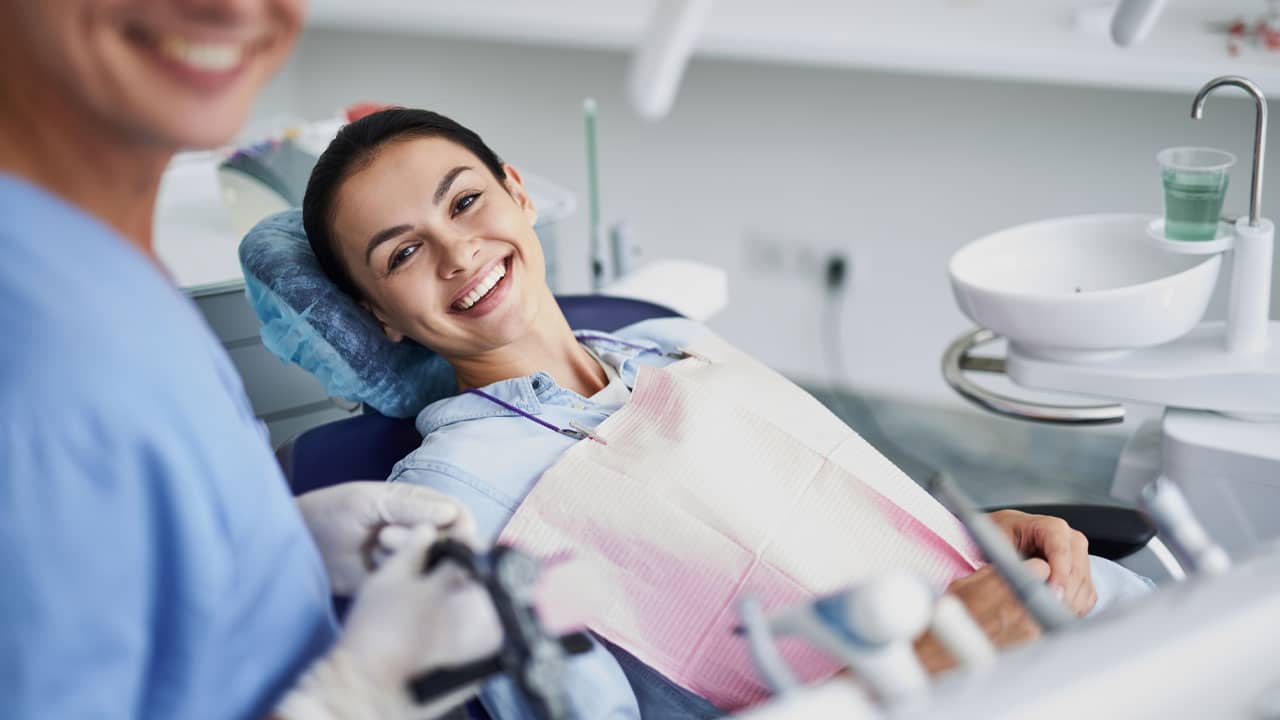 Woman sitting in dental chair smiling at camera
