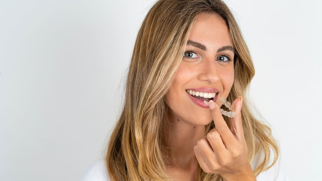 Woman holding a dental aligner smiling