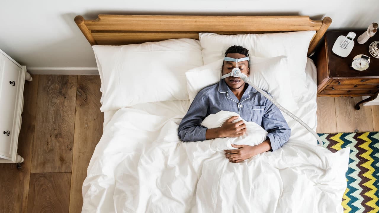Man sleeping in bed with sleep apnea device