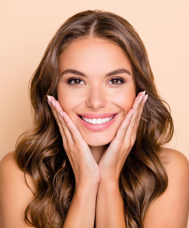 Young woman smiling confidently with hands on chin after a cosmetic dental smile makeover